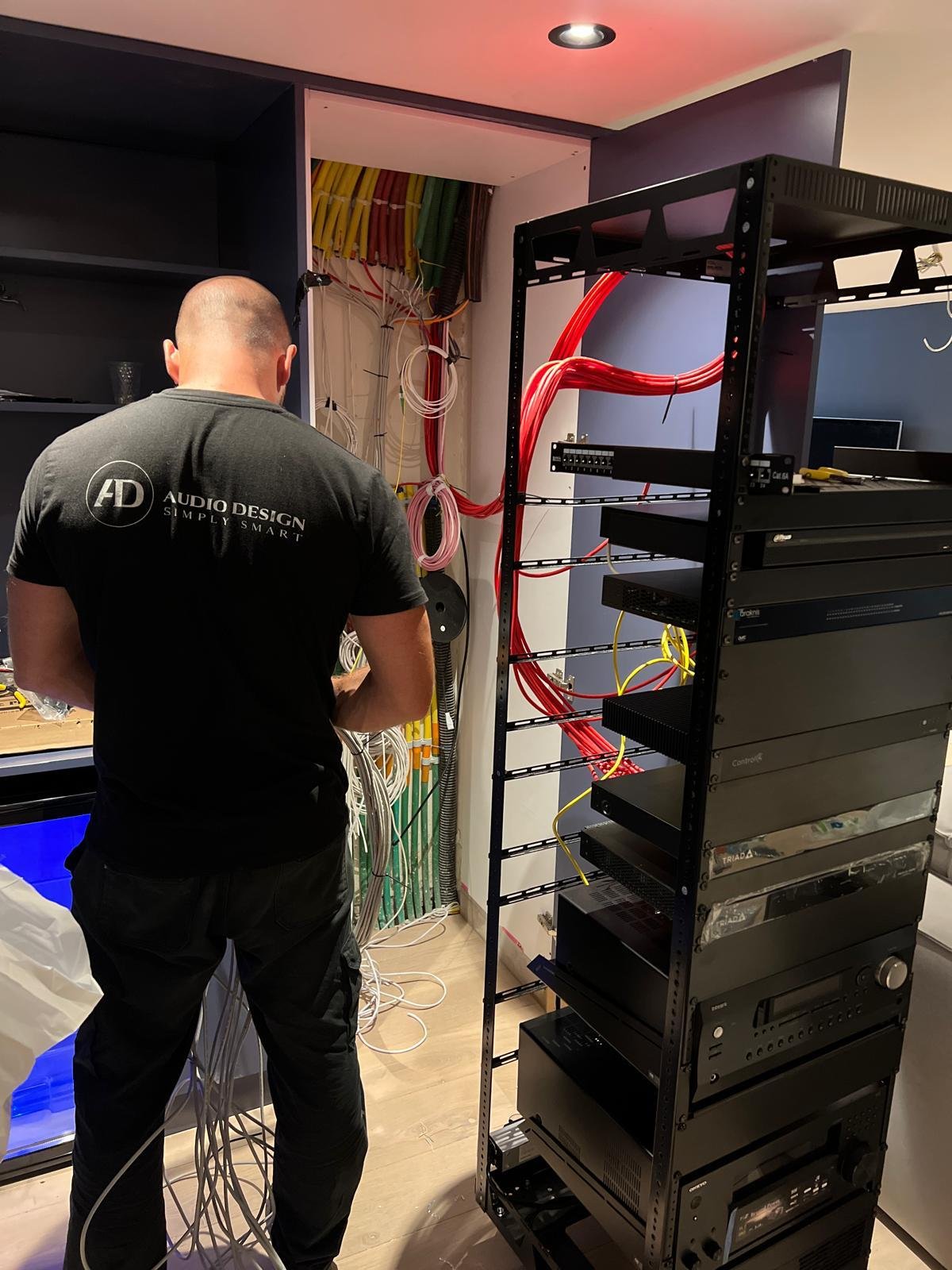 מתקין של Audio Design מחבר ארון תקשורת, עם חיווט מסודר בצבעים